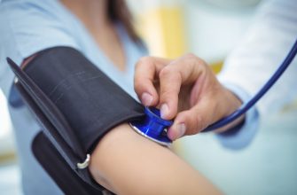 Close-up of a clinician inflating a blue blood pressure cuff around a patient’s upper arm during a checkup.