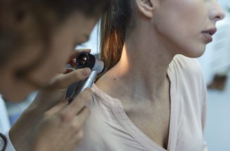 Healthcare professional examines a woman's ear with an otoscope during a medical checkup.