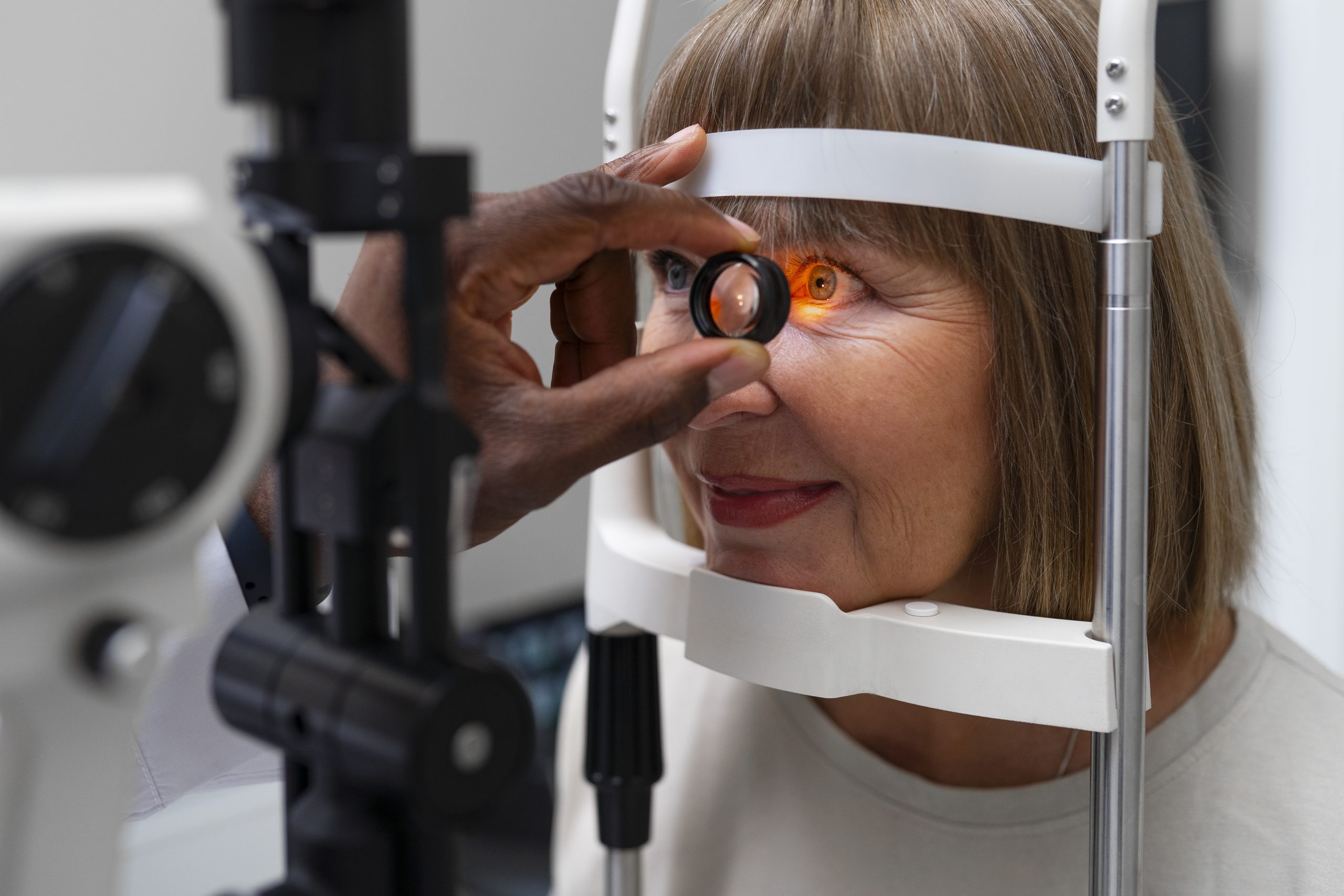 Woman undergoing an eye exam with a slit lamp, looking into the device.