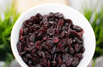 Dried cranberries in a white bowl seen in a close-up on green blurred background