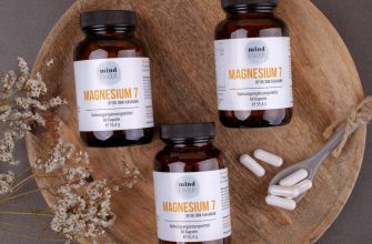 Brown glass supplement bottles labeled Magnesium 7 on a round wooden board, with dried flowers and white capsules nearby.