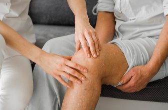 Caregiver stabilizing and examining an elderly person's knee during a therapy session.