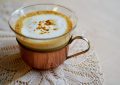 Latte or cappuccino in a glass mug with frothy milk on a lace tablecloth.