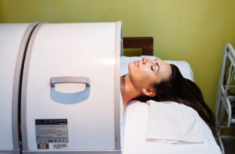 Person undergoing an MRI scan with their head inside the scanner, resting on a pillow and covered with a white gown/blanket.